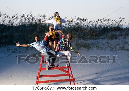 Hippies hanging out at the beach climbing on lifeguard chair View Large Photo Image Stock Photo - Hippies hanging out at the beach climbing on lifeguard chair. Fotosearch