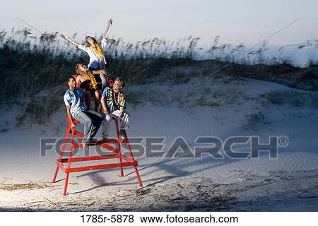 Stock Photo - Hippies hanging out at the beach climbing on lifeguard chair. Fotosearch