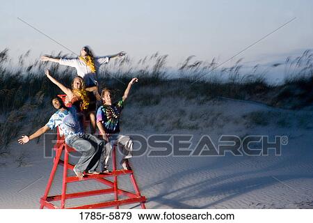 Stock Photo - Hippies hanging out at the beach climbing on lifeguard chair. Fotosearch
