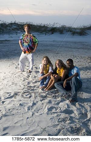 Hippies sitting on sand at beach at dusk View Large Photo Image Stock Image - Hippies sitting on sand at beach at dusk. Fotosearch