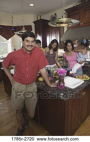 Stock Image - Indian family in kitchen preparing food. Fotosearch