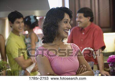 Indian woman smiling in kitchen with her family in background View Large Photo Image Stock Image - Indian woman smiling in kitchen with her family in background. Fotosearch