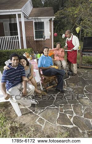 Stock Image - Interracial couple and family enjoying backyard barbeque. Fotosearch