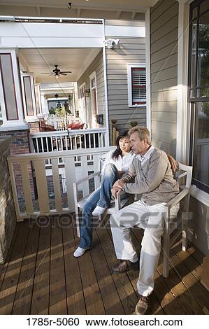 Stock Image - Interracial couple sitting on the front porch. Fotosearch