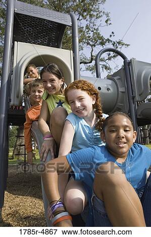 Laughing children sitting on a slide at a playground View Large Photo Image Stock Photo - Laughing children sitting on a slide at a playground. Fotosearch