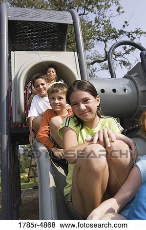 Laughing children sitting on a slide at a playground View Large Photo Image Stock Photo - Laughing children sitting on a slide at a playground. Fotosearch