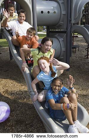 Laughing children sitting on a slide at a playground View Large Photo Image Stock Photograph - Laughing children sitting on a slide at a playground. Fotosearch
