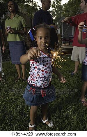 Stock Photo - Little girl on 4th of July playing with sparkler. Fotosearch
