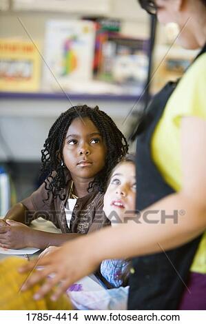 Little girls looking up at teacher in class View Large Photo Image Picture - Little girls looking up at teacher in class. Fotosearch