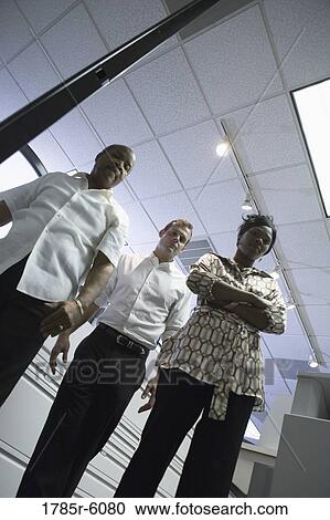 Stock Image - Long angle portrait of three business people in an office. Fotosearch