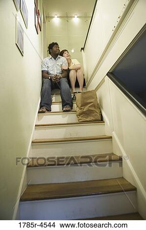 Low angle view of a young inter-racial couple sitting on top of a stairway View Large Photo Image Picture - Low angle view of a young inter-racial couple sitting on top of a stairway. Fotosearch