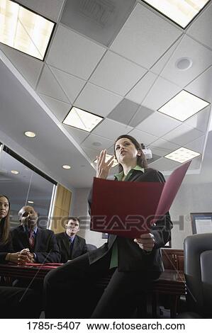 Low angle view of business men and women at a presentation in a formal conference room View Large Photo Image Stock Photo - Low angle view of business men and women at a presentation in a formal conference room. Fotosearch