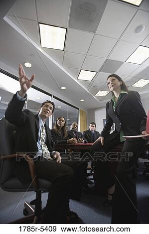 Low angle view of business men and women at a presentation in a formal conference room View Large Photo Image Stock Photo - Low angle view of business men and women at a presentation in a formal conference room. Fotosearch