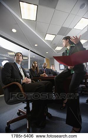Low angle view of business men and women at a presentation in a formal conference room View Large Photo Image Stock Photograph - Low angle view of business men and women at a presentation in a formal conference room. Fotosearch