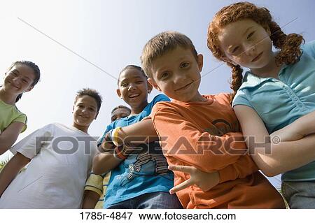 Low angle view of children with folded arms standing together at a playground View Large Photo Image Stock Photo - Low angle view of children with folded arms standing together at a playground. Fotosearch