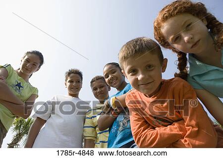 Low angle view of children with folded arms standing together at a playground View Large Photo Image Stock Photo - Low angle view of children with folded arms standing together at a playground. Fotosearch