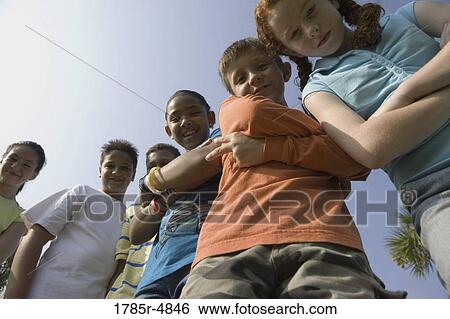 Low angle view of children with folded arms standing together at a playground View Large Photo Image Stock Photograph - Low angle view of children with folded arms standing together at a playground. Fotosearch