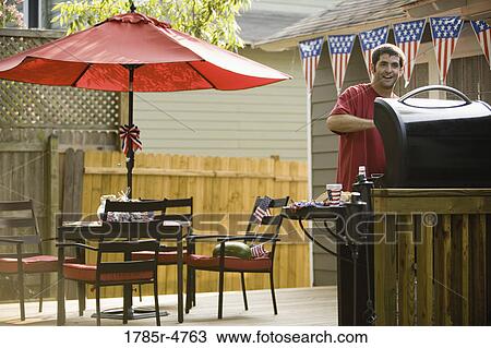 Man cooking on outdoor grill on backyard patio on 4th of July View Large Photo Image Stock Image - Man cooking on outdoor grill on backyard patio on 4th of July. Fotosearch