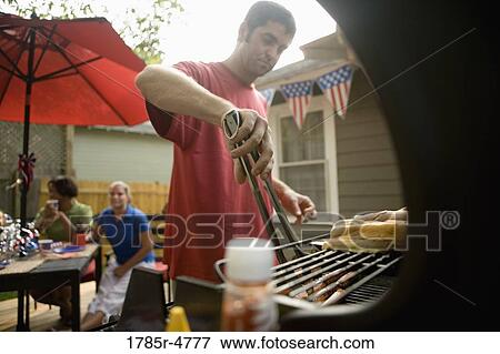 Man grilling hotdogs on the 4th of July View Large Photo Image Stock Photo - Man grilling hotdogs on the 4th of July. Fotosearch