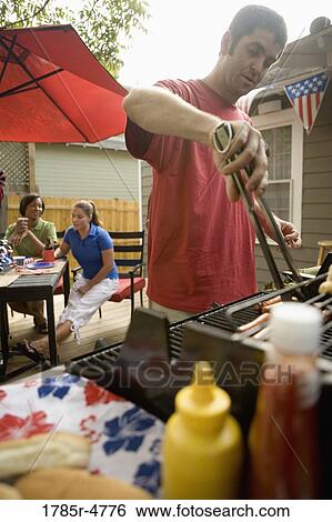 Man grilling hotdogs on the 4th of July View Large Photo Image Stock Photograph - Man grilling hotdogs on the 4th of July. Fotosearch