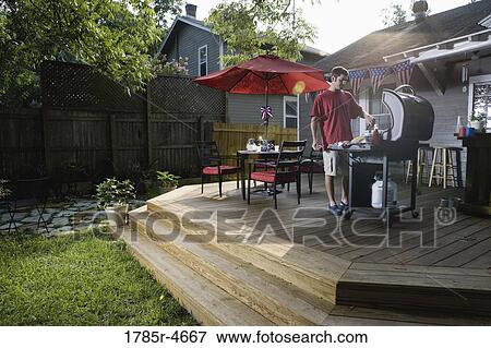 Man grilling on backyard patio on 4th of July View Large Photo Image Stock Photo - Man grilling on backyard patio on 4th of July. Fotosearch