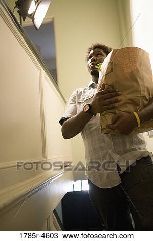 Man holding a grocery bag filled with groceries View Large Photo Image Stock Image - Man holding a grocery bag filled with groceries. Fotosearch