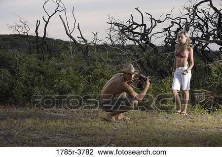 Stock Image - Man photographing a scantily clad woman. Fotosearch