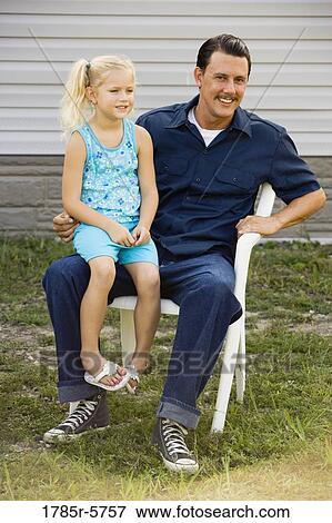 Man sitting outside on chair with daughter on his lap View Large Photo Image Stock Photo - Man sitting outside on chair with daughter on his lap. Fotosearch