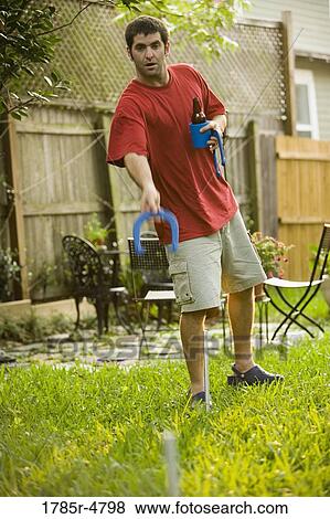 Man tossing horseshoes in backyard View Large Photo Image Stock Photo - Man tossing horseshoes in backyard. Fotosearch