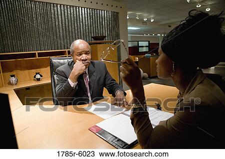 Mature business man seated behind desk interviewing younger woman View Large Photo Image Stock Image - Mature business man seated behind desk interviewing younger woman. Fotosearch