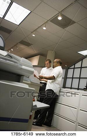 Mature businessman conferring with younger male colleague in an office View Large Photo Image Stock Photo - Mature businessman conferring with younger male colleague in an office. Fotosearch