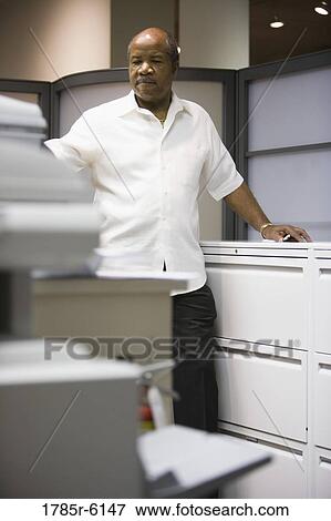 Stock Photo - Mature businessman standing in an office cubicle. Fotosearch