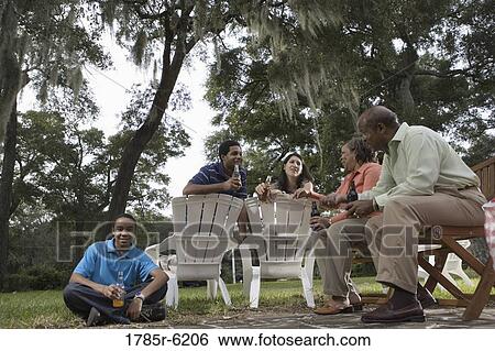 Mature couple and their son having drinks with inter-racial couple while sitting on lawn chairs View Large Photo Image Stock Photograph - Mature couple and their son having drinks with inter-racial couple while sitting on lawn chairs. Fotosearch