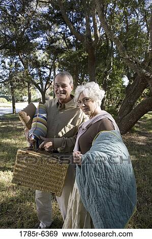 Mature couple carrying picnic basket and blanket View Large Photo Image Stock Photo - Mature couple carrying picnic basket and blanket. Fotosearch