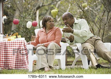 Stock Image - Mature couple conversing next to picnic table. Fotosearch