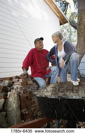 Mature couple conversing next to stack of bricks outside house View Large Photo Image Stock Photography - Mature couple conversing next to stack of bricks outside house. Fotosearch