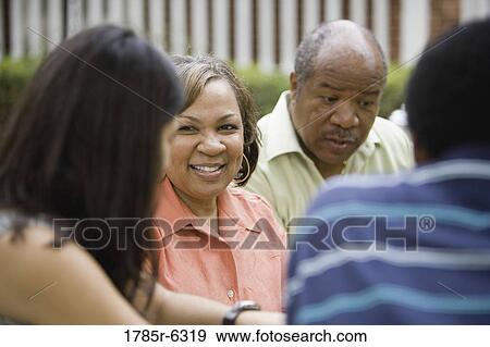 Mature couple conversing with others in foreground View Large Photo Image Stock Photo - Mature couple conversing with others in foreground. Fotosearch