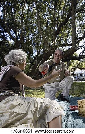 Mature couple having a picnic enjoying wine View Large Photo Image Stock Image - Mature couple having a picnic enjoying wine. Fotosearch