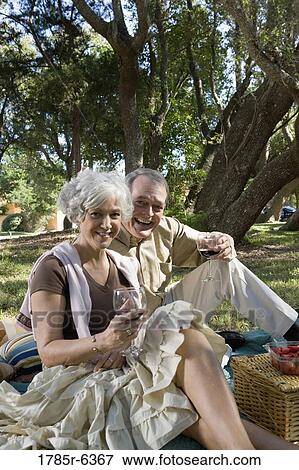 Mature couple having a picnic enjoying wine View Large Photo Image Stock Photo - Mature couple having a picnic enjoying wine. Fotosearch
