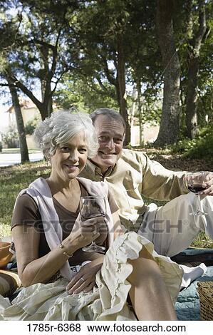 Mature couple having a picnic enjoying wine View Large Photo Image Stock Photo - Mature couple having a picnic enjoying wine. Fotosearch