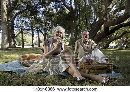 Mature couple having a picnic enjoying wine View Large Photo Image Stock Photograph - Mature couple having a picnic enjoying wine. Fotosearch