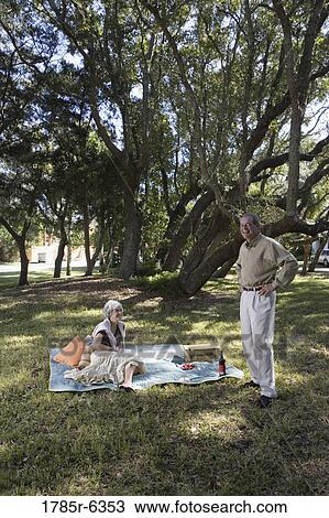 Stock Image - Mature couple having a picnic in a park. Fotosearch