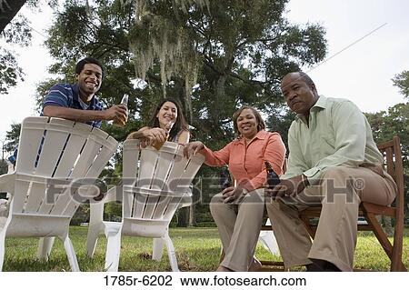 Mature couple having drinks with inter-racial couple while sitting on lawn chairs View Large Photo Image Stock Image - Mature couple having drinks with inter-racial couple while sitting on lawn chairs. Fotosearch