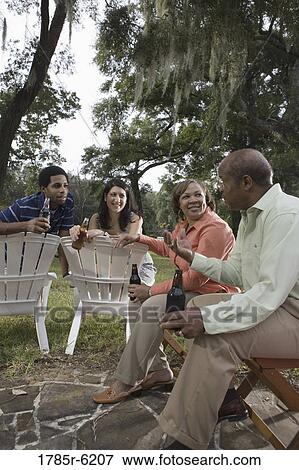 Mature couple having drinks with inter-racial couple while sitting on lawn chairs View Large Photo Image Stock Photo - Mature couple having drinks with inter-racial couple while sitting on lawn chairs. Fotosearch