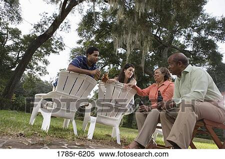 Mature couple having drinks with inter-racial couple while sitting on lawn chairs View Large Photo Image Stock Photography - Mature couple having drinks with inter-racial couple while sitting on lawn chairs. Fotosearch