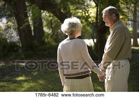 Stock Image - Mature couple holding hands in the park. Fotosearch