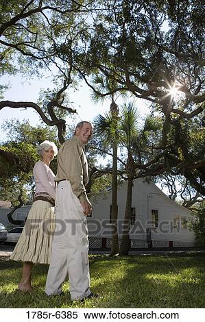 Stock Photography - Mature couple holding hands under oak trees. Fotosearch