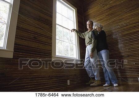 Mature couple in a darkened room leaning against window, gazing out View Large Photo Image Picture - Mature couple in a darkened room leaning against window, gazing out. Fotosearch
