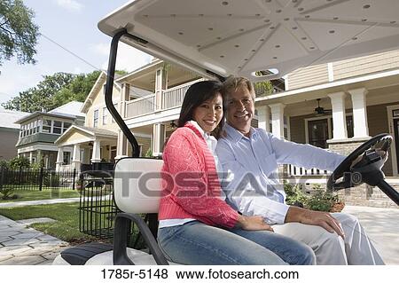 Mature couple riding golf cart through the neighborhood View Large Photo Image Stock Photo - Mature couple riding golf cart through the neighborhood. Fotosearch