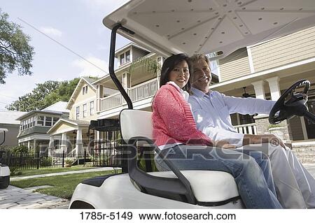 Mature couple riding golf cart through the neighborhood View Large Photo Image Stock Photo - Mature couple riding golf cart through the neighborhood. Fotosearch